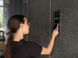 teenage girl using phone scan to digital door lock security systems at home.