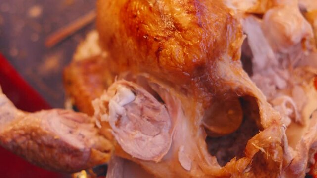 Roasted Turkey Leg Being Carved from Main Joint with Sharp Knife at Dinner Table for Christmas or Thanksgiving Dinner. Serving Traditional Homemade Food at Xmas to Celebrate 4K.