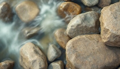 Close-up of smooth rocks submerged in a gently flowing stream, with clear water reflecting light