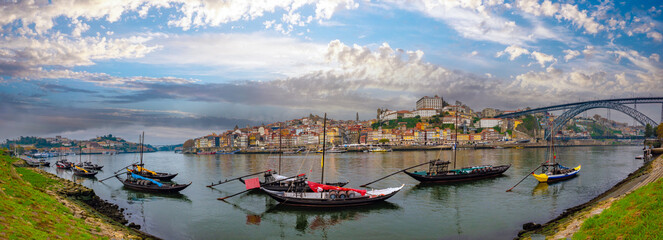 Fototapeta premium Panoramic view of the old city of Porto from the quays of Gaia on the opposite shore of the Douro river, with traditional Port wine trading vessels in the foregound, Oporto, Portugal