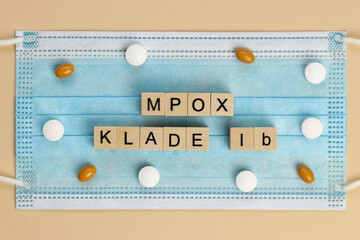 Mpox Klade Ib (Clade in German) is laid out with wooden cubes on a surgical face mask, surrounded by various pills. MPOX is the new name for the monkeypox virus.