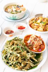 Delicious Asian dishes on a dining table. Spicy crispy morning glory salad, spicy clear soup with fresh herbs and stir-fried squid with curry powder