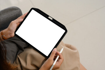 Cropped image of a woman holding digital tablet with blank desktop screen sitting on sofa