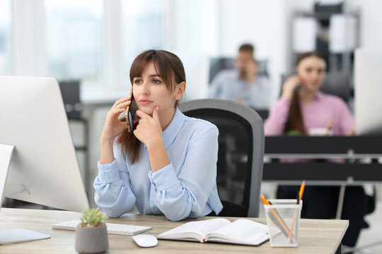 Saleswoman talking on phone at desk in office
