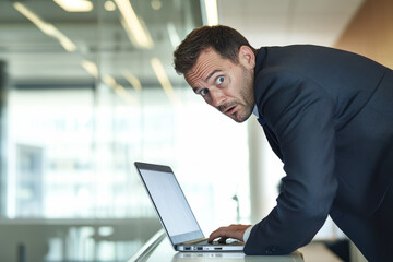 Caucasian male adult in office setting looking surprised at laptop