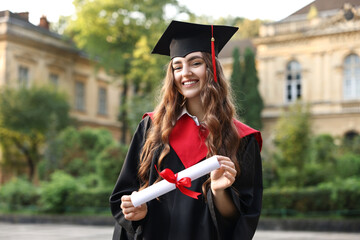 Happy student with diploma after graduation ceremony outdoors