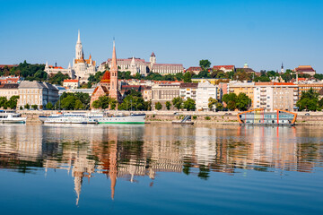 Cityscape of Budapest featuring the Fisherman's Bastion and Matthias Church on the Buda side of the city with the moored boats on the riverbank of the Danube River