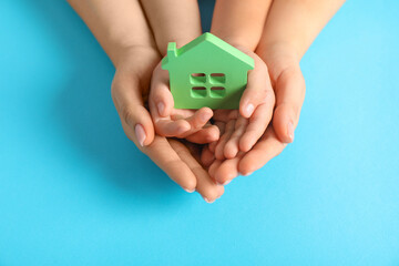 Adoption concept. Woman and kid with cutout of house at light blue background, top view