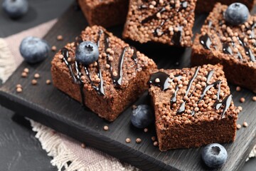 Delicious chocolate puffed rice bars and blueberries on gray table, closeup