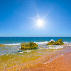 sandy sea beach with huge stones at the summer sunny day