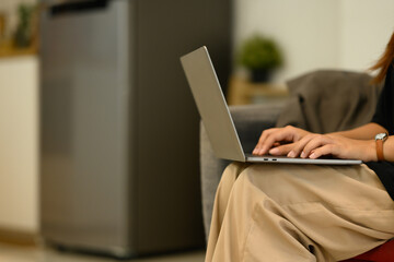 Cropped shot young woman using laptop, working remotely at home