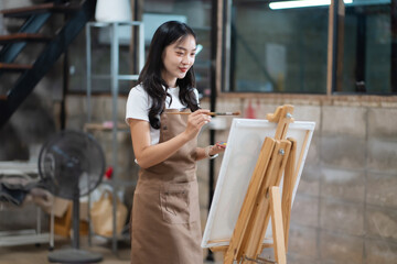 Fototapeta premium Young female artist painting on canvas in the home studio, fine arts and creativity concept.