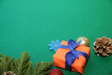 Season's greetings scene.Share your warm wishes with this image idea.view of magnificent giftbox with ribbon, sparkling ornaments, frosty fir, ball, cone on green backdrop, ready for personalized ad