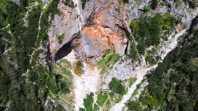 Majestic rinka waterfall flows down rocky cliffs into the lush green logarska dolina valley, creating a breathtaking natural wonder in the slovenian alps
