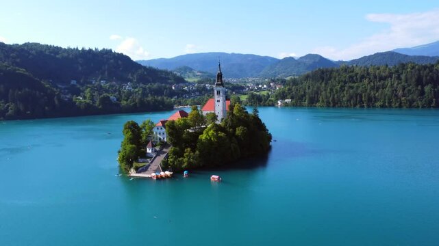 Aerial view of lake bled featuring the assumption of mary church on a small island, with kayakers enjoying summer in the julian alps