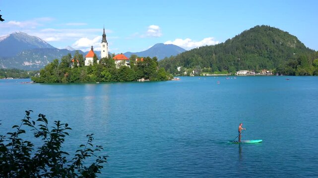 Kayaker paddling on the beautiful lake bled in slovenia, enjoying the stunning view of bled island and the julian alps on a sunny summer day