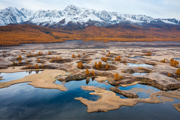 Serene autumn view of a vibrant plain with lakes and distant snow-covered peaks.