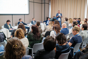 Obraz premium Attendees sit in audience, participating in a seminar with speakers discussing professional topics.