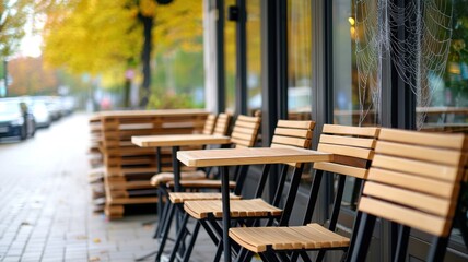 Outdoor café with wooden chairs, tables amd 
spider web in autumn setting.