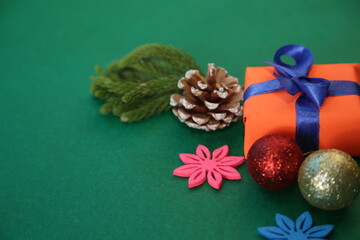 Season's greetings scene.Share your warm wishes with this image idea.view of magnificent giftbox with ribbon, sparkling ornaments, frosty fir, ball, cone on green backdrop, ready for personalized ad