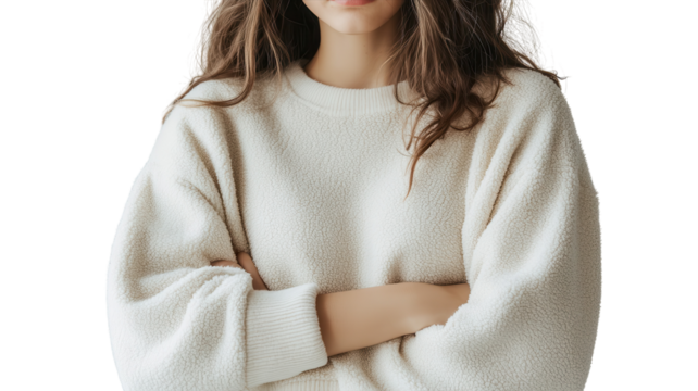 Young woman standing with crossed arms, wearing a cozy light sweater, in a neutral setting, showcasing a thoughtful expression.
