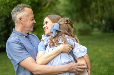 Happy family embracing in green park, sharing a tender moment