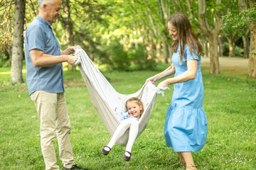 Fototapeta premium Happy family playing with blanket swing in park