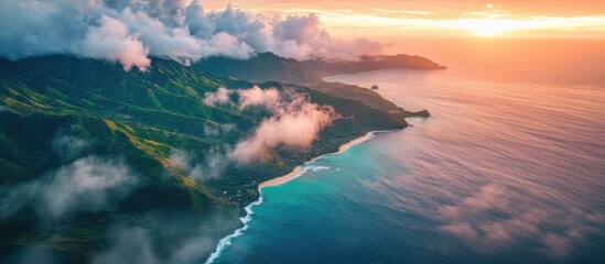 Aerial view of lush green mountains meeting the ocean with dramatic clouds during a vibrant sunset captured from above using a drone