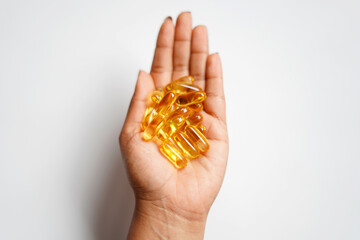 hand holding golden color cod liver capsules