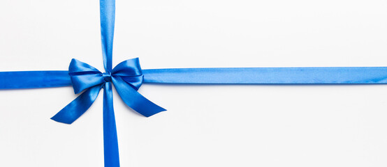 Top view of blue ribbon rolled and blue bow isolated on colored background. Flat lay with copy space