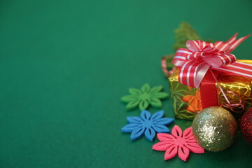 Season's greetings scene.Share your warm wishes with this image idea.view of magnificent giftbox with ribbon, sparkling ornaments, frosty fir, ball, cone on green backdrop, ready for personalized ad
