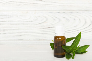 Natural Mint Essential Oil in a Glass Bottle. organic cosmetics with herbal extracts of mint on colored background