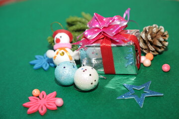 Christmas festivity theme. view of beige present packages, sophisticated tree ornaments, baubles, handcrafted star, mistletoe sprigs, snowman on green backdrop, space for ad
