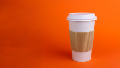 Paper coffee cup on orange backdrop. Mug for drink. Environmentally friendly, recyclable