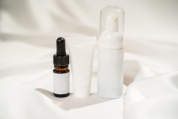 Minimalist Skincare Product Display with Lotion Bottle, Cream Jar, and Serum Dropper on White Background