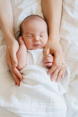 Baby sleeping in arms of his loving mother. Baby care.