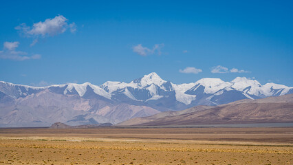 Colorful high altitude mountain landscape with snowcapped ridge in desert on Pamir Highway near Karakul, Murghab, Gorno-Badakhshan, Tajikistan