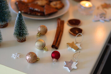 Various Christmas decorations, cookies, chocolate, nuts and tangerines, wine glasses and lit candles on the table. Holiday hygge at home. Selective focus.