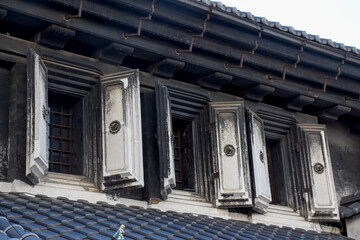 A warehouse window in Kawagoe, Japan, features traditional wooden shutters, intricate iron details, and a rustic finish, showcasing the historic charm and functionality of Edo-period architecture.