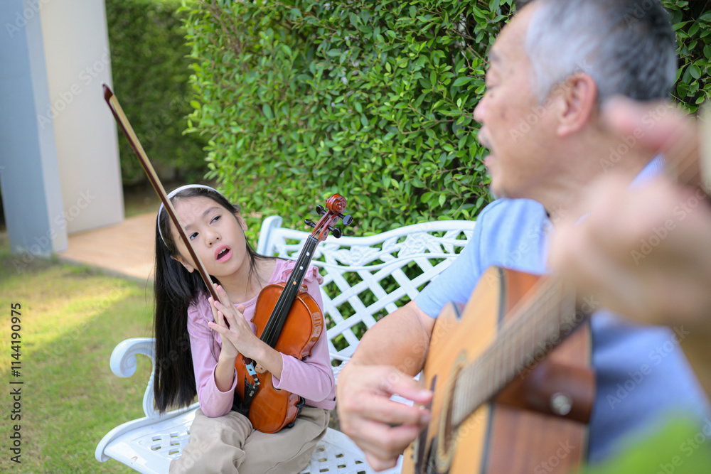 Wall mural A girl violinist and her grandfather practice music together in the garden at home