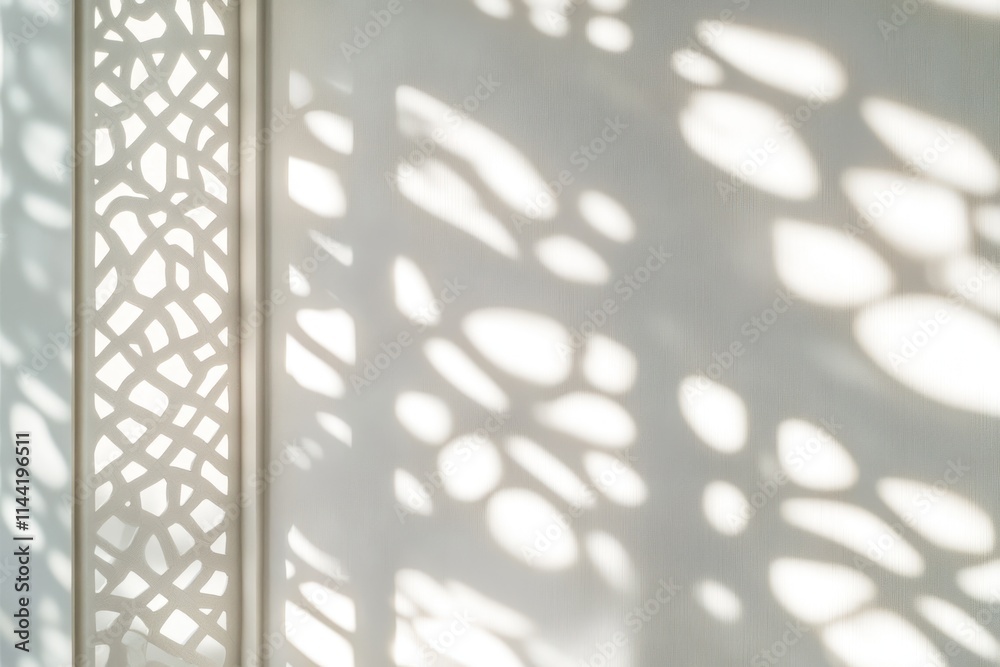 Poster Light and shadow patterns cast on white wall by decorative lattice.
