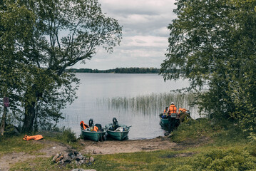 Boats moored on shore of lake, traveling on water of river in dinghy