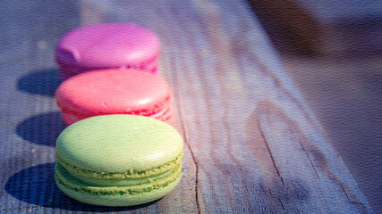 Three macarons of different colors are sitting on a wooden table