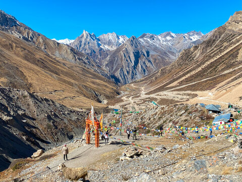 Sacred gate with flags and temple bell on the road leading to Om Parvat. Sheshnag Parvat, a snake-shaped mountain, in the background