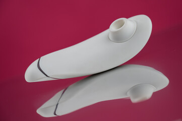 Clitoral vibrator on mirrored pink surface. 
