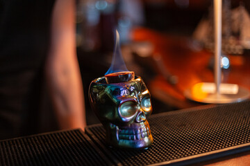 glass of skull with an alcoholic cocktail and passion fruit burns on the bar counter. Zombie cocktail
