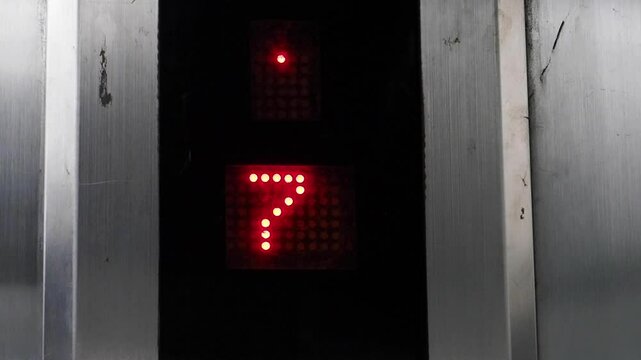 Close-up slow-motion of an elevator screen showing changing floor numbers as the elevator ascends