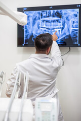 vertical Dentist pointing at teeth x-ray on digital screen in clinic