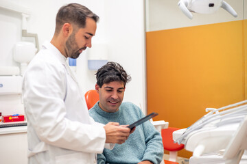 Dentist showing x-ray to patient on a digital tablet in dental clinic © EDER