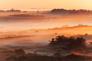 Beautiful sunrise at Lighthouse of Rubjerg Knude. Denmark north coast with wonderfully illuminated fog.